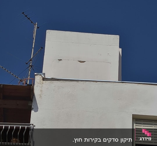 אנטנה על גג מבנה לבן עם שמיים כחולים